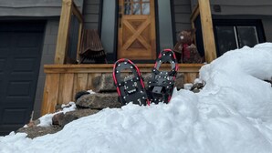 Ein Holzhaus mit einer verschneiten Veranda und einem verschneiten Dach.