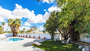A backyard with a swimming pool, a lawn, and a variety of potted plants. - 3BR Palm Springs Oasis (Palm Springs)
