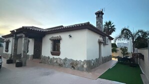 Einbungalow mit Ziegeldach, Stein Fundament und einem kleinen Vorgarten mit künstlichem Rasen.