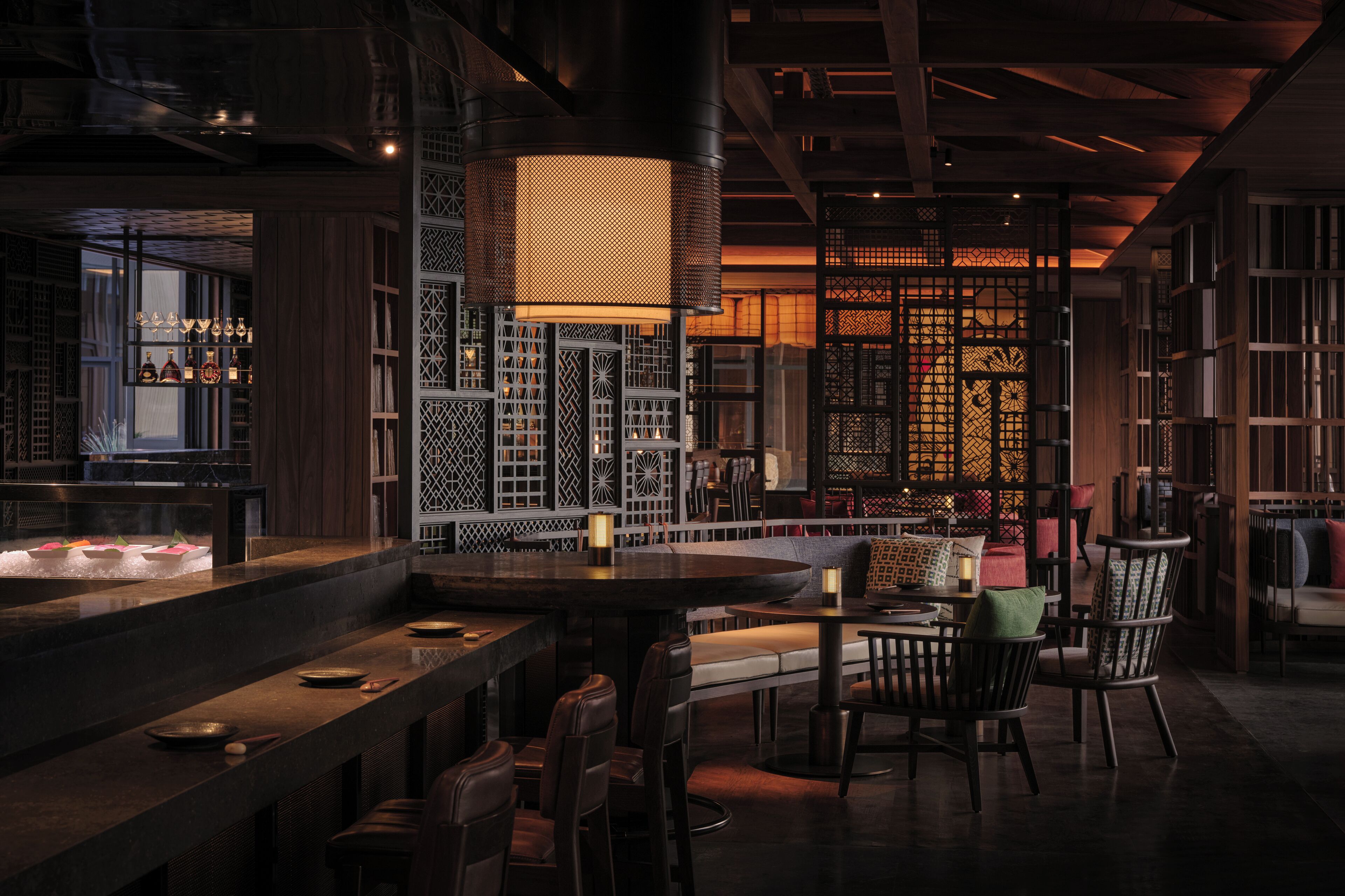 A dimly lit restaurant with wooden furniture, a bar area, and decorative screens.