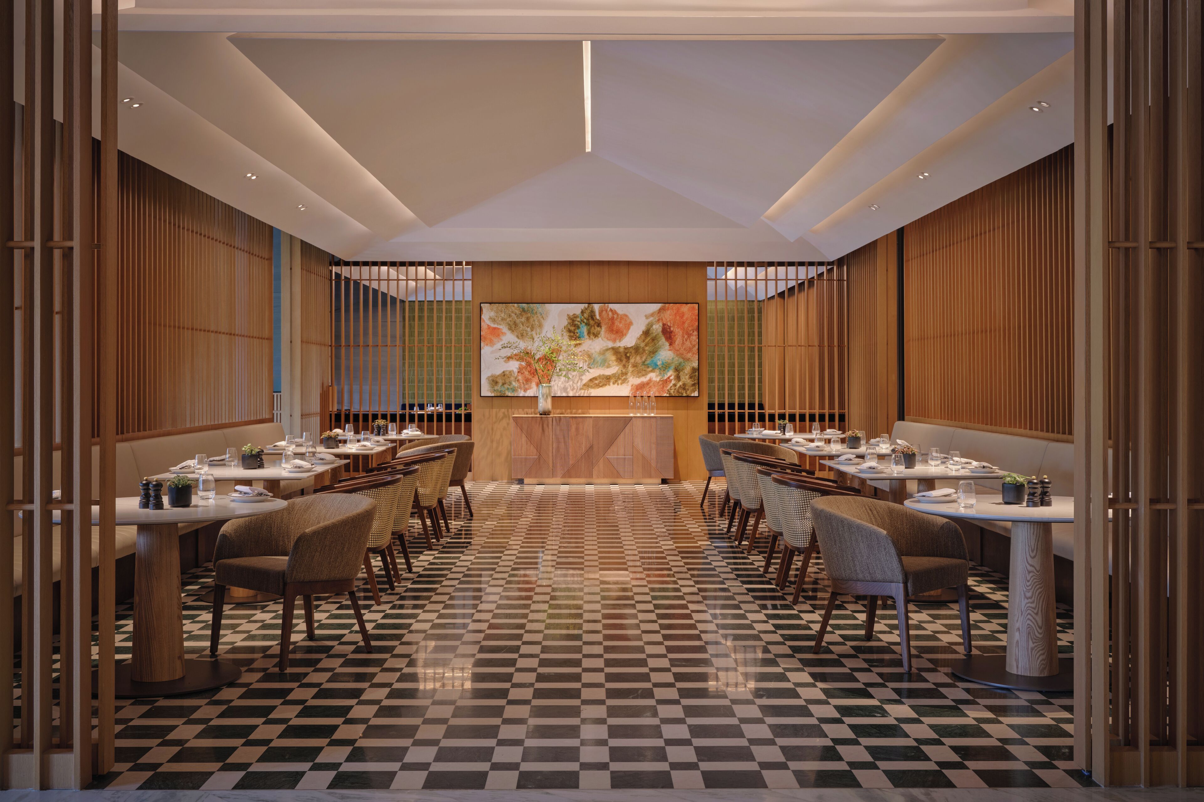 A restaurant with a checkered floor, wooden panel walls, and a central island.