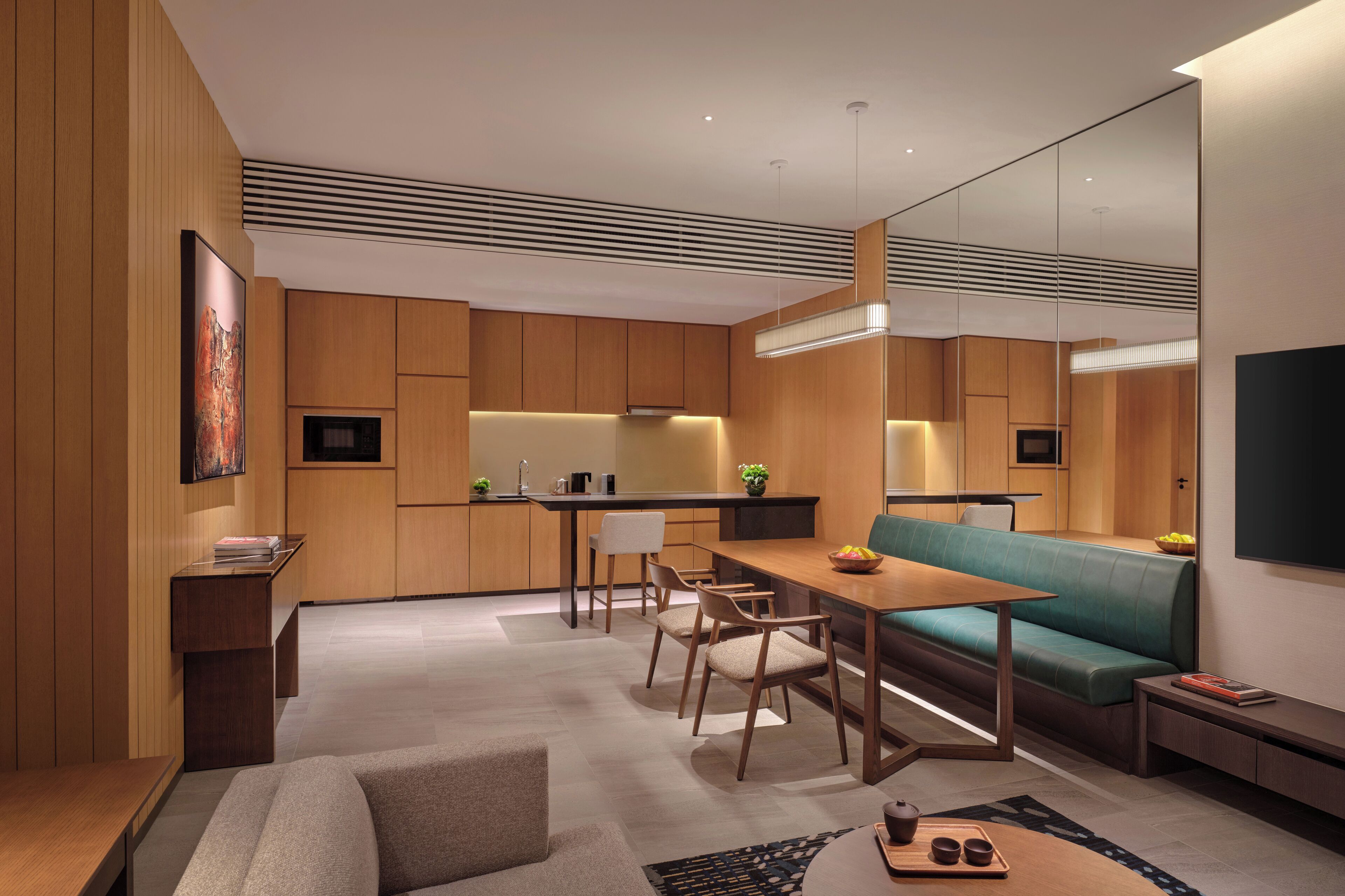 Una sala moderna con comedor de madera, un sofá y una cocina al fondo.