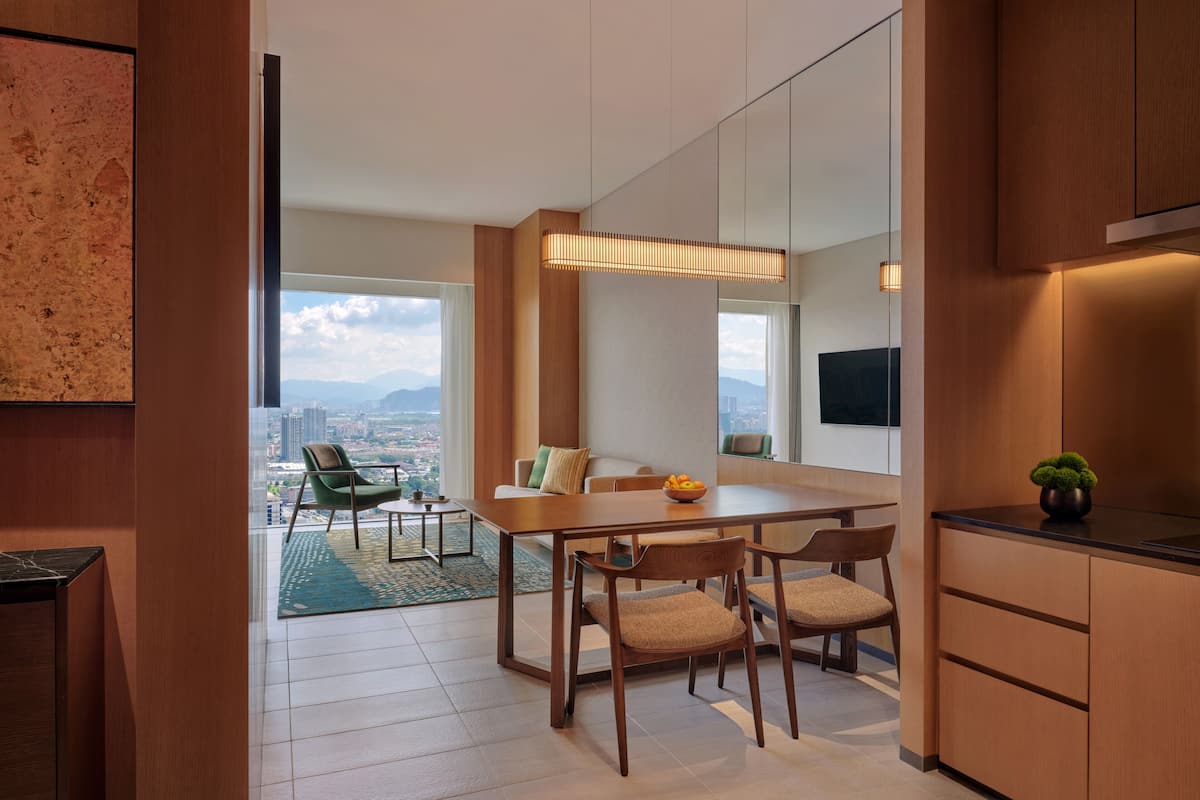 Una cocina moderna con armarios de madera, un comedor con mesa y sillas, y vistas de la ciudad a través de amplios ventanales.