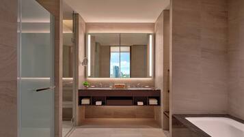 A modern bathroom with a glass shower enclosure, a large mirror, and a bathtub.