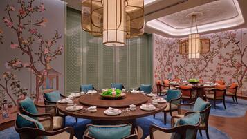 Una mesa redonda para comer con sillas, rodeada de arte floral en las paredes y paneles de celosía china tradicionales.