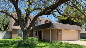 A residential house with a garage, a tree in front, and a well-maintained lawn. - Spacious 5-bedroom house in marvelous Boise with AC, WiFi (Boise)