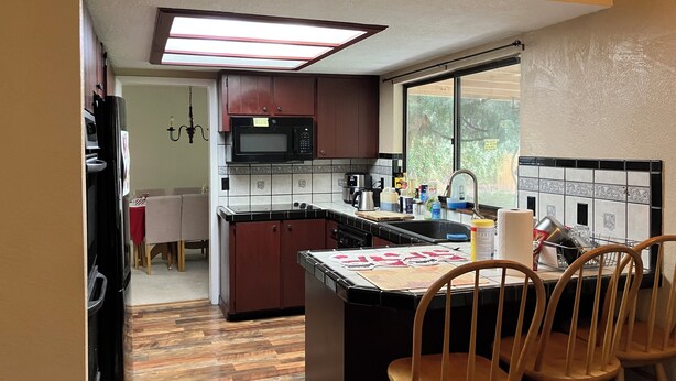 A compact kitchen with a microwave, sink, and wooden chairs. - Spacious 5-bedroom house in marvelous Boise with AC, WiFi (Boise)