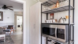 Une cuisine moderne équipée d'un four à micro-ondes et d'un four encastrés, ainsi que d'une étagère en métal noir pour ranger les ustensiles de cuisine.