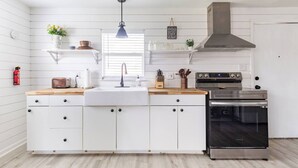 Une cuisine moderne avec des meubles blancs, un four en acier inoxydable et un plan de travail en bois.