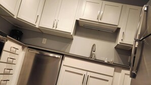 A modern kitchen with white cabinets, stainless steel appliances, and a wooden floor. - Downtown Suite Living! (Minneapolis)