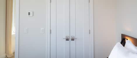 Une chambre à coucher avec un lit, une armoire et un thermostat fixé au mur.