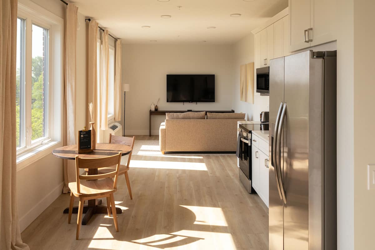 A modern kitchen with a dining area, a flat-screen TV, and a large refrigerator.