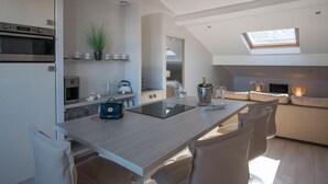 A modern kitchen with a central island, built-in appliances, and a skylight. - O Carré Croisette (Cannes)