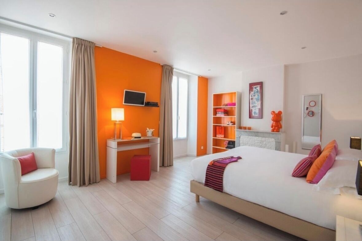 Ein modernes Hotelzimmer mit einem großen Bett, einem Schreibtisch, einem Sessel und einem Fernseher.