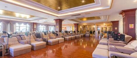 A spacious hotel lobby with a polished wooden floor, multiple seating areas, and a grand ceiling.