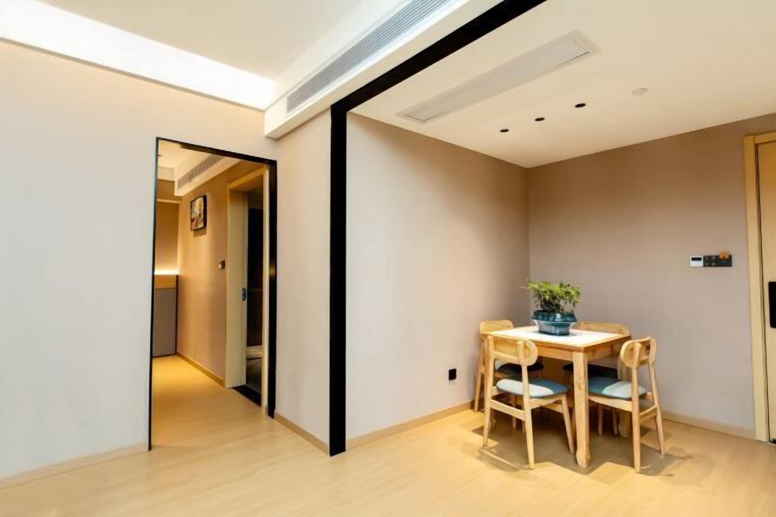 A modern interior with a wooden dining table, chairs, and a potted plant.