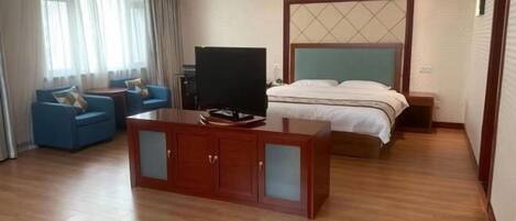 Ein Hotelzimmer mit Bett, Fernseher, Schreibtisch und einer Sitzecke mit Stühlen.