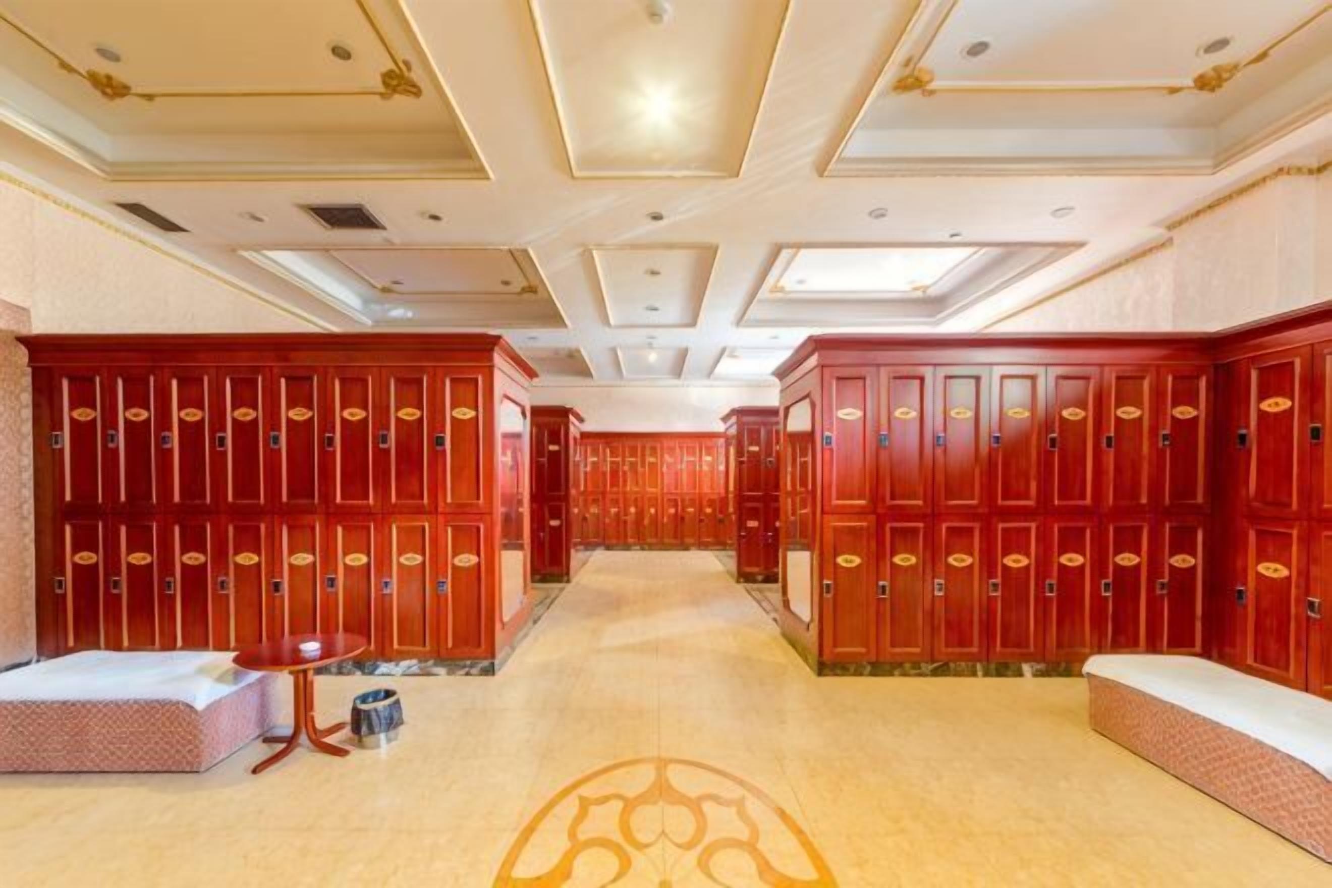 A hotel lobby with rows of wooden lockers, a reception desk, and a patterned carpet.