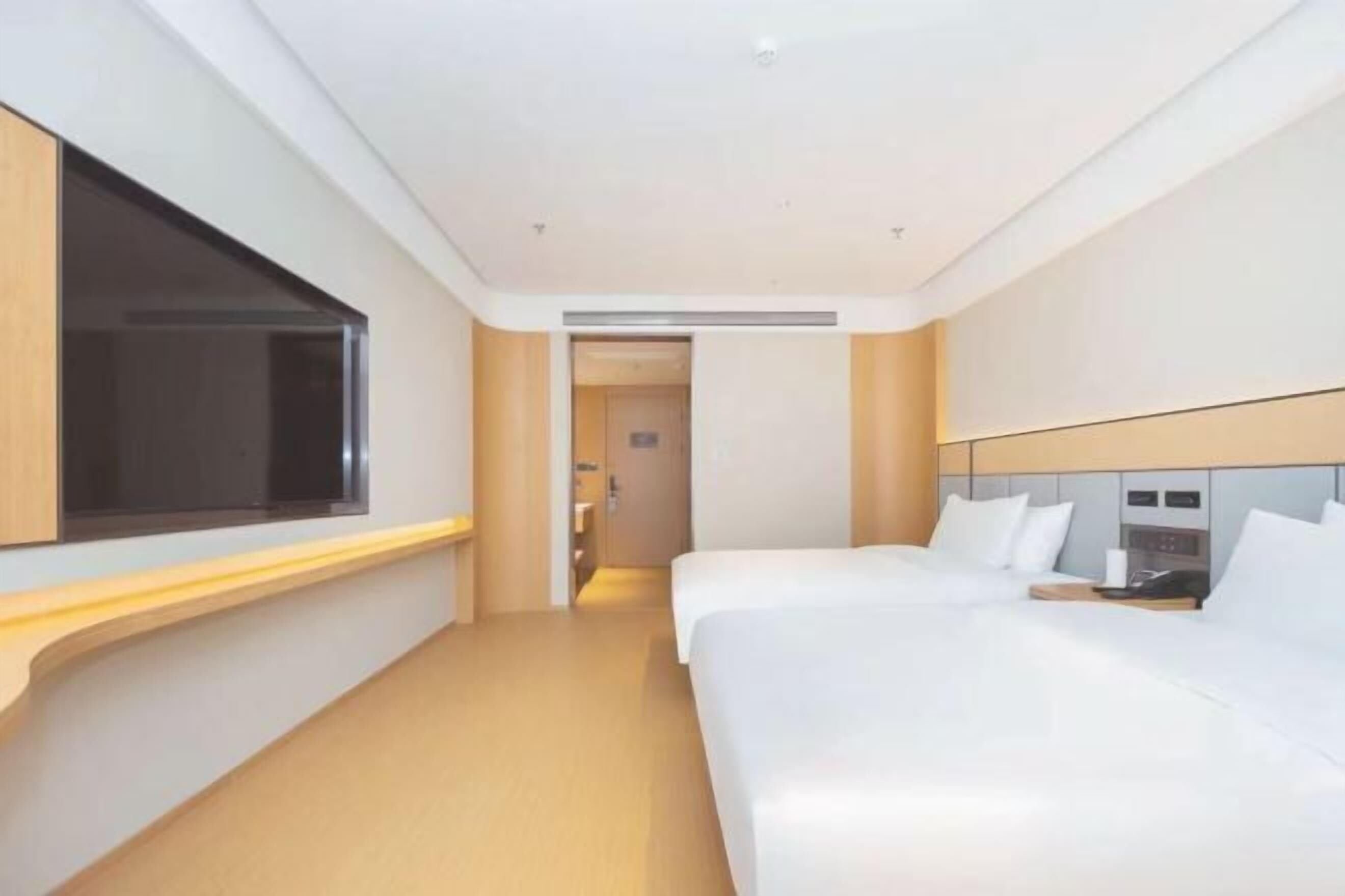 A hotel room with a large bed, a bedside table, a window, and a door leading to a bathroom.