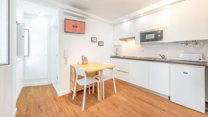 Een moderne keuken met witte kasten, een houten eettafel en een inbouwmagnetron.