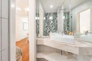 Een moderne badkamer met een grote spiegel, twee wastafels en een decoratieve spatwand.