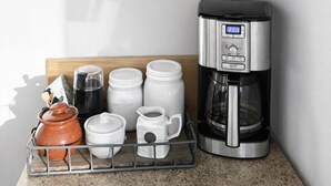 Eine Küche mit Holzböden, die Küchenutensilien, eine Kaffeemaschine und ein Schild mit der Aufschrift "l'affeine it my sunny" beherbergt.