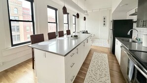 A modern kitchen with a central island, large windows, and a view of the city.