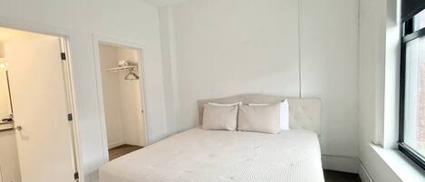 Un dormitorio con cama, vestidor y ventana.