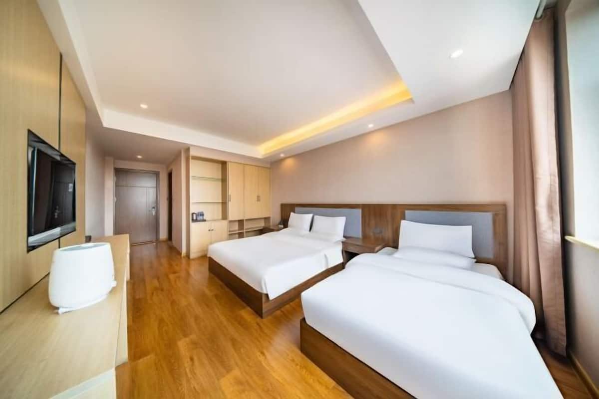 Une chambre d’hôtel avec deux lits, une télévision, un bureau et une salle de bain.