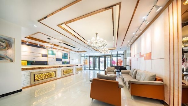 A modern lobby with a reception desk, sofas, and a chandelier. - Hongxin Hotel (Ulan)