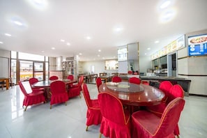 Zona pranzo con tavolo rotondo e sedie rosse, cucina sullo sfondo e vista esterna.