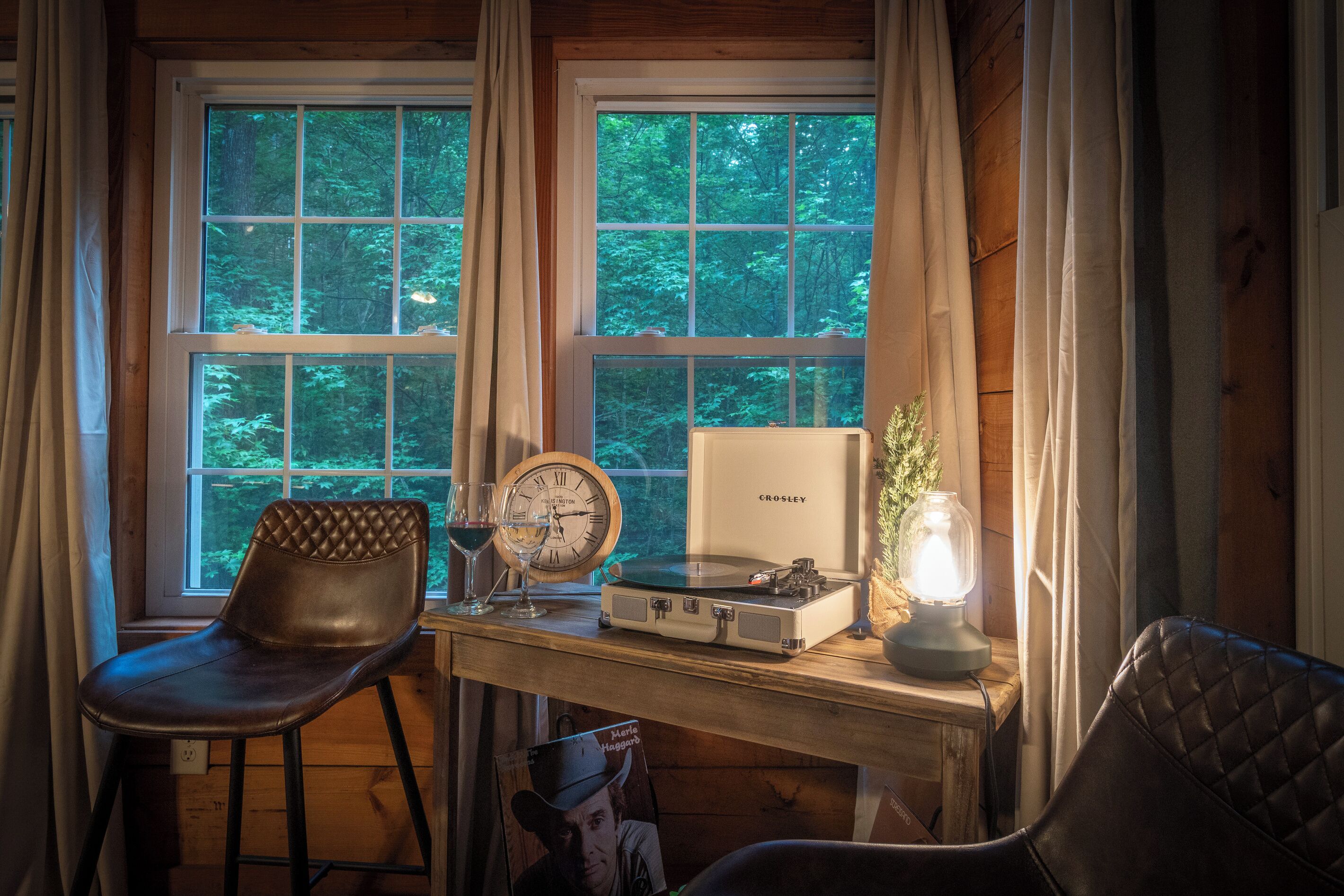 A wooden interior with a desk, a clock, a record player, and a chair.