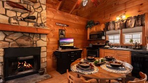 Ein gemütliches Blockhaus-Interieur mit Kamin aus Stein, Holztisch und Küchenzeile.