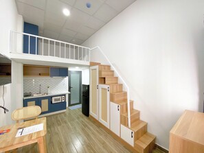 Un appartement compact comprenant une kitchenette, un coin repas et un escalier.