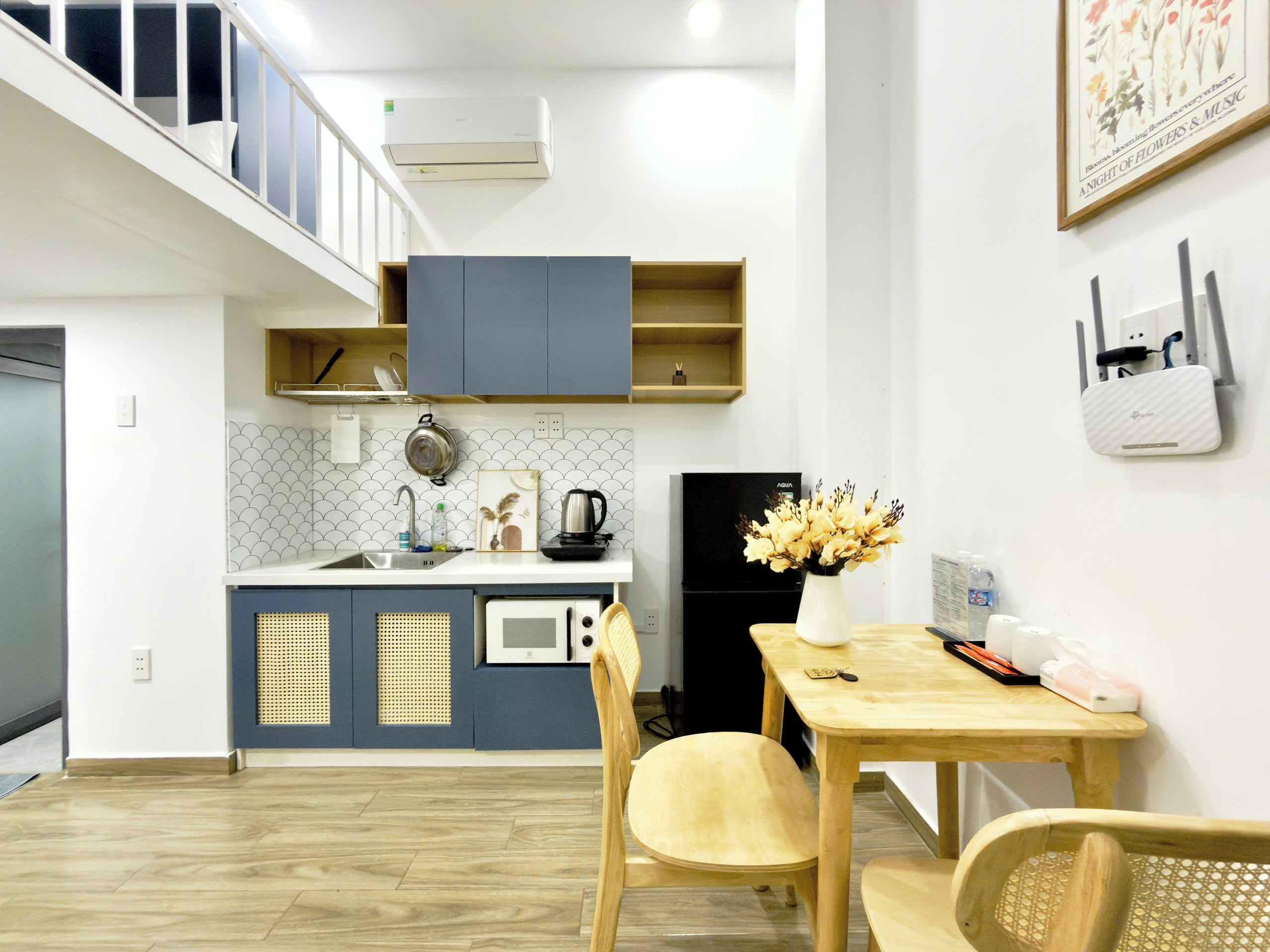 A compact kitchen with a microwave, stove, and sink. There is a dining area with a table and chairs.