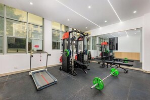 A gym with exercise equipment, a mirror, and large windows. - Xiangjiang Hotel Shishi (Shishi)