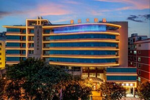 A multi-story hotel with a modern design, featuring a prominent entrance and a series of balconies. - Xiangjiang Hotel Shishi (Shishi)