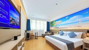 A hotel room with a large bed, a TV, a desk, and a painting of a beach scene. - Xiangjiang Hotel Shishi (Shishi)