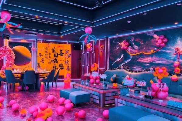A room with a large mural, a sofa, a coffee table, and a dining area.
