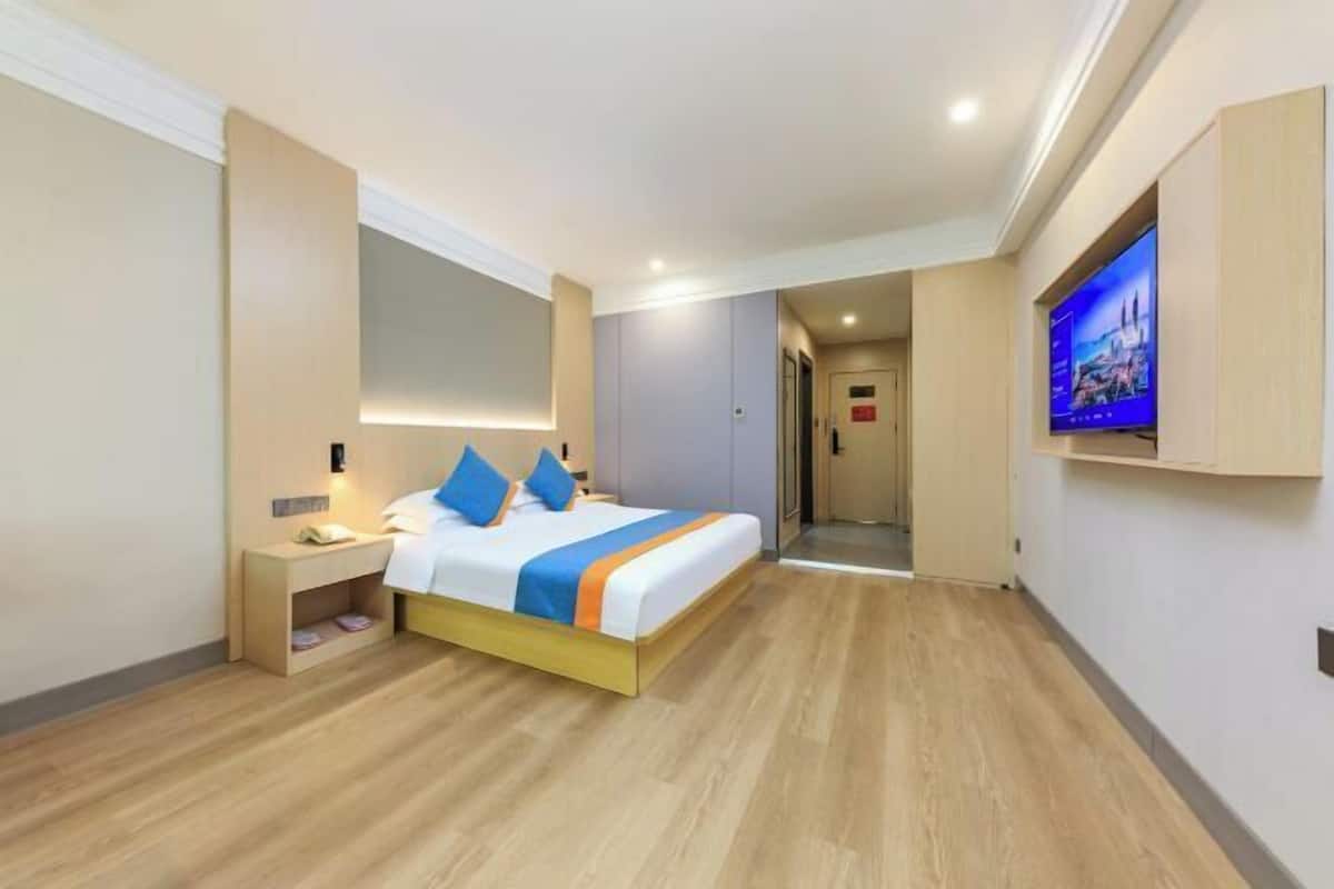 Een hotelkamer met een bed, nachtkastje, televisie en spiegel.