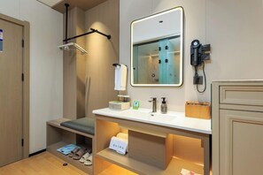 Ein modernes Badezimmer mit Dusche, Waschtisch und Spiegel sowie einem Telefon.