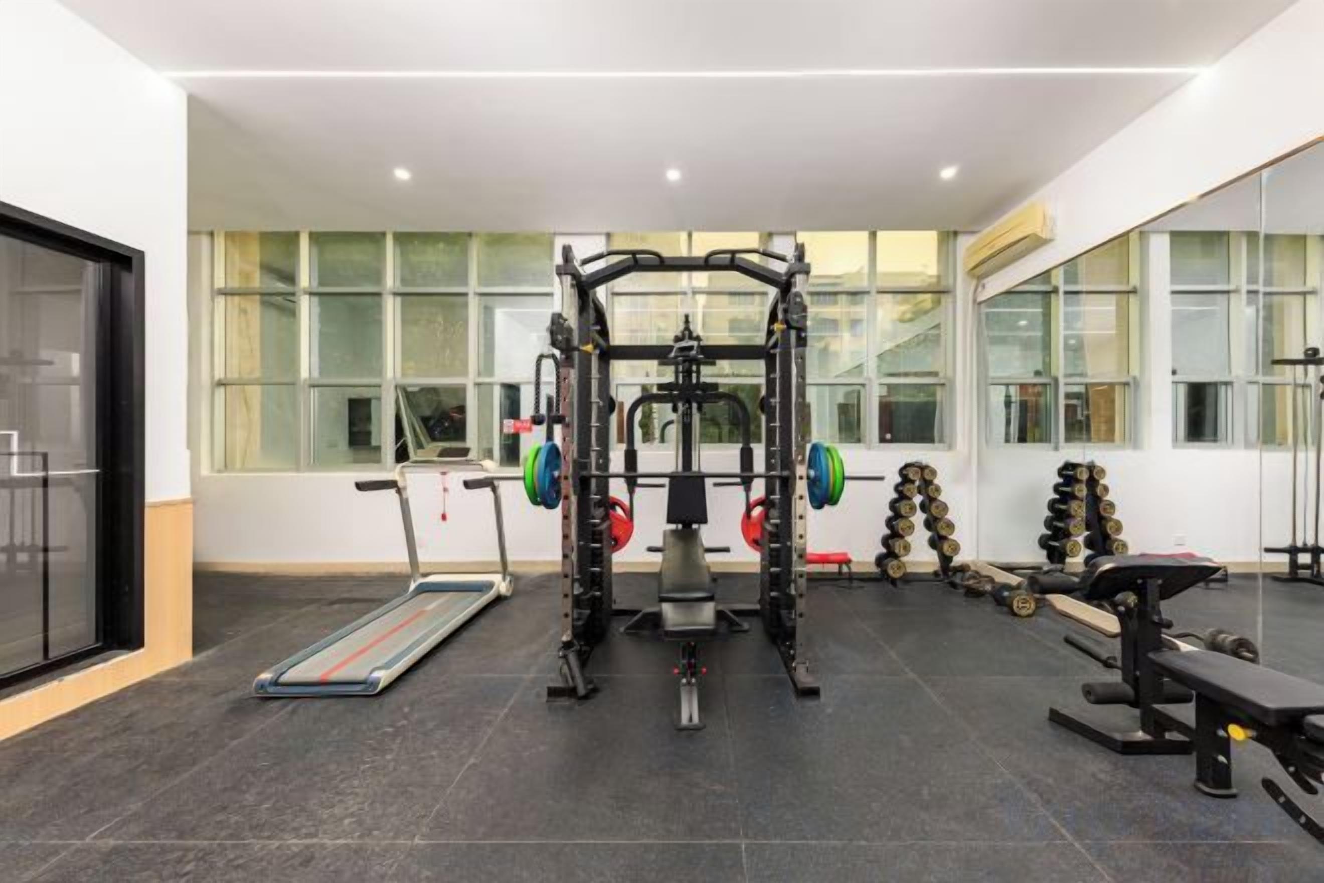 A gym with weightlifting equipment, treadmills, and benches.