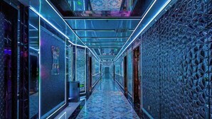 A corridor with patterned floor tiles, glass walls, and a textured wall on the right. - Xiangjiang Hotel Shishi (Shishi)