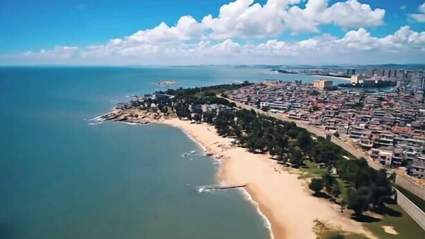 An aerial view of a coastal city with a beach, dense urban area, and a clear sky. - Xiangjiang Hotel Shishi (Shishi)