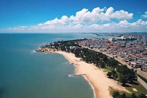 An aerial view of a coastal city with a beach, dense urban area, and a clear sky. - Xiangjiang Hotel Shishi (Shishi)