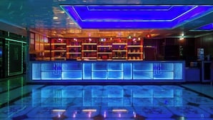 A bar area with a modern design, featuring illuminated shelves and a reflective floor. - Xiangjiang Hotel Shishi (Shishi)