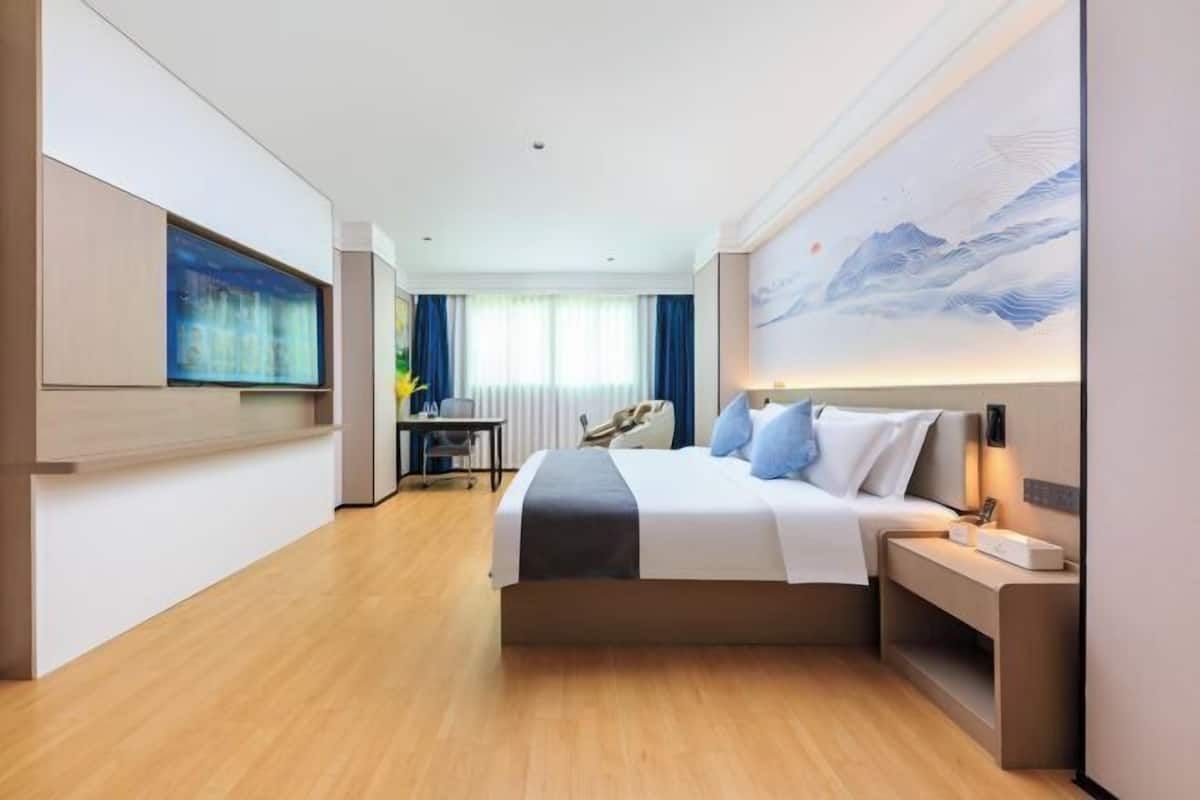 Een moderne hotelkamer met een groot bed, een bureau, een stoel en een schilderij aan de muur.