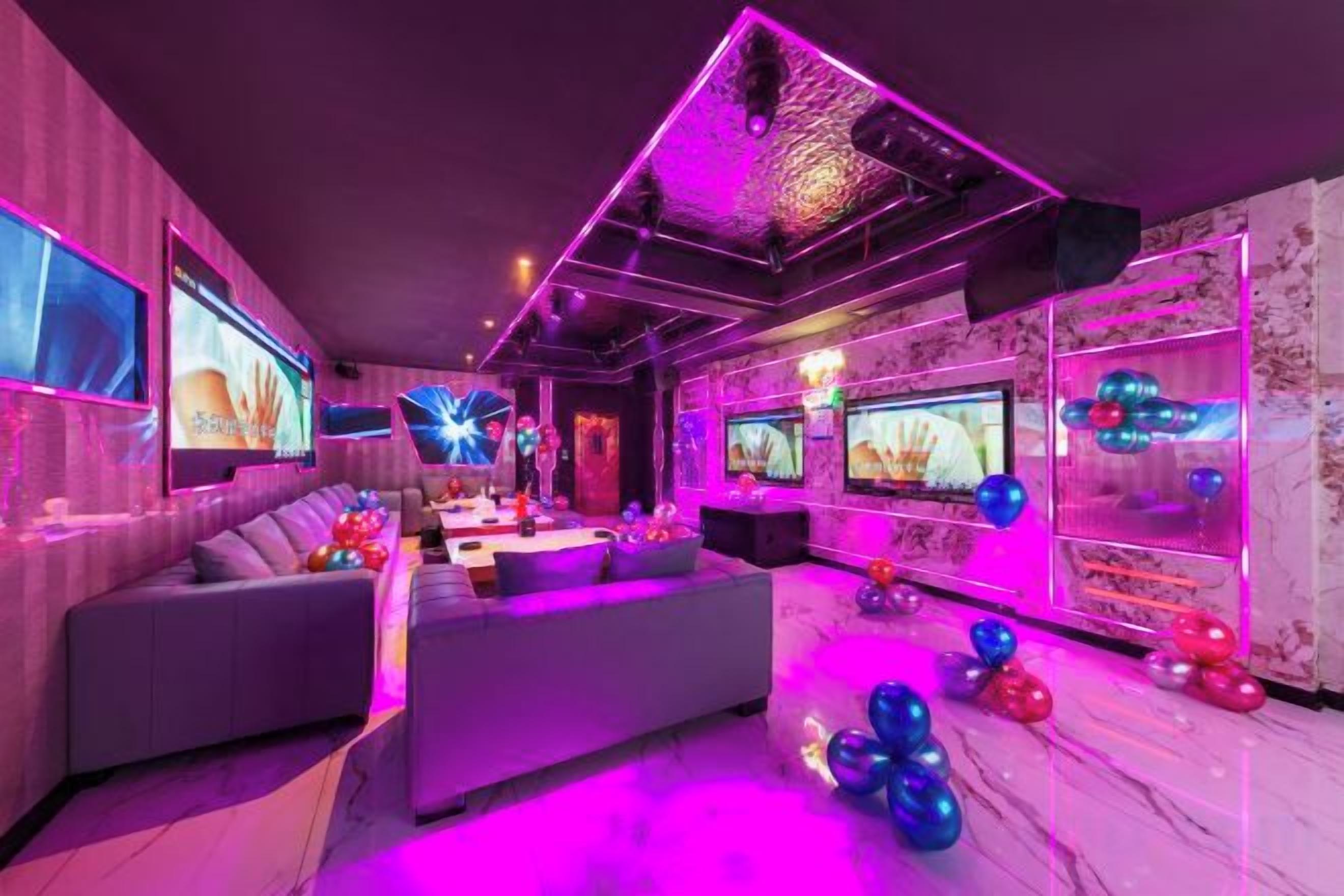 A modern lounge with sofas, a bar area, and a large screen.