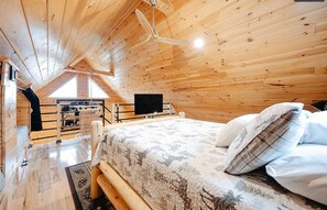 Une chambre confortable en bois, avec un lit, une télévision et une fenêtre donnant sur un paysage magnifique.