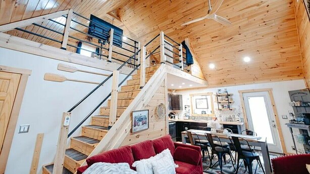 A wooden interior with a staircase leading to an upper level, a dining area, and a kitchen. - Cozy 2BR 2Bath Cabin, minutes from OU, Hocking Hills, Zaleski Forest. (Albany)